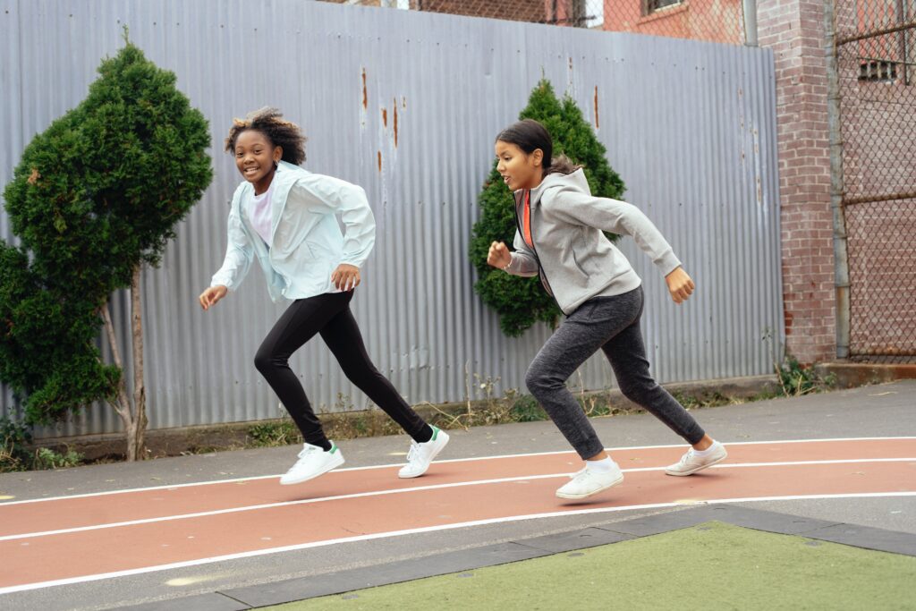 Two girls running as physical activity is crucial for navigating school life with type 1 diabetes.