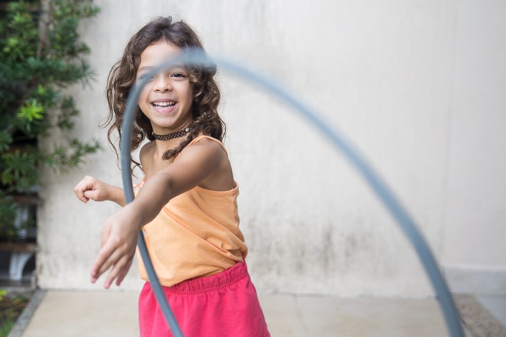 A girl smiling as she plays with a hula hoop
