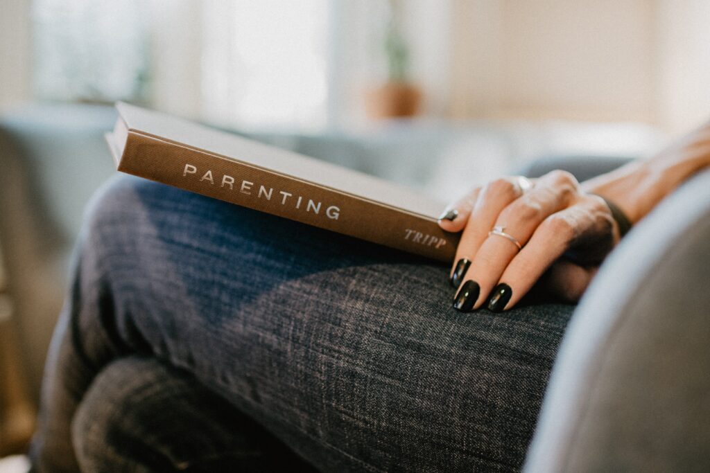 Person holding a book titled "Parenting"